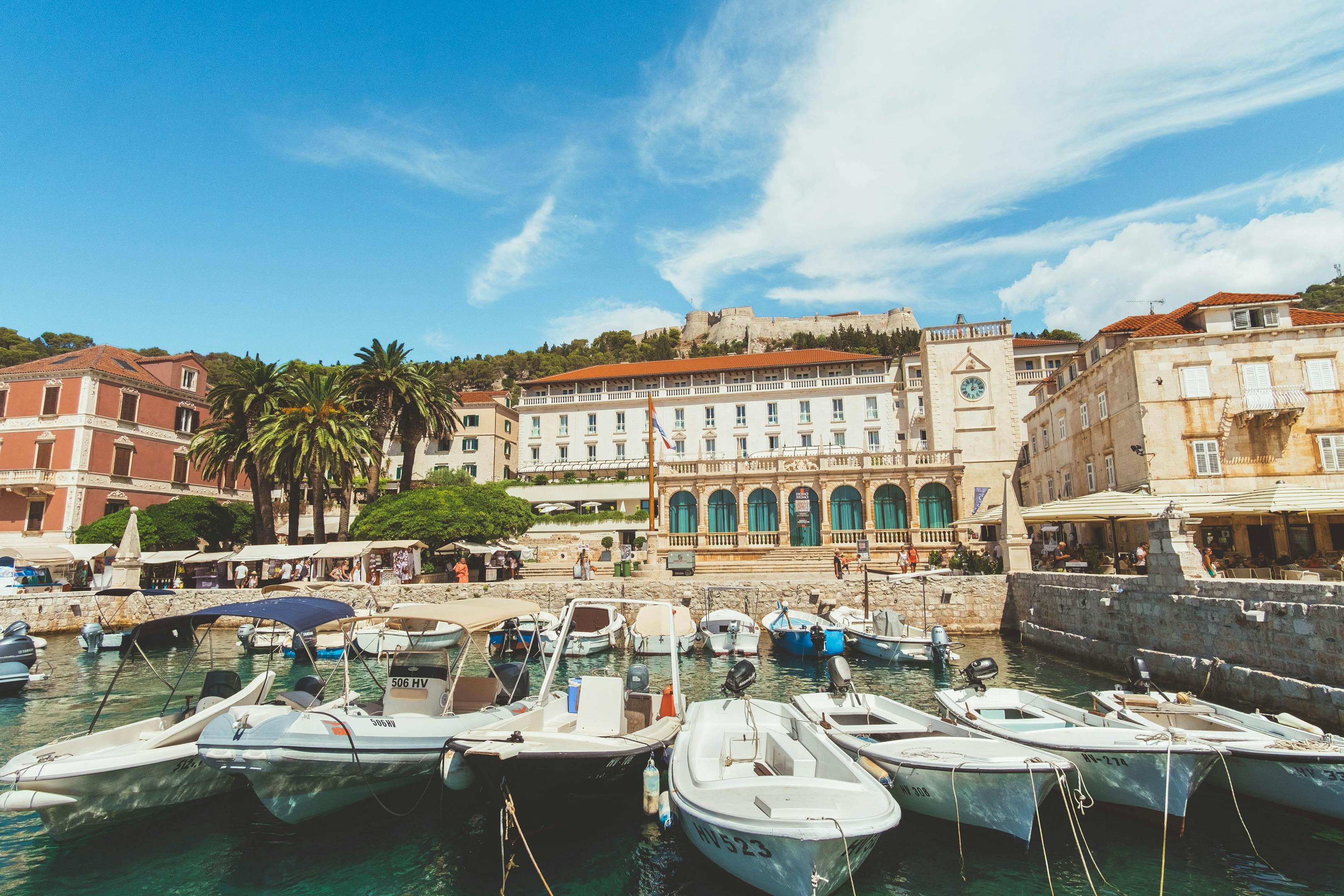 Charming harbor scene in Hvar, Croatia, capturing boats and historical architecture under a bright blue sky