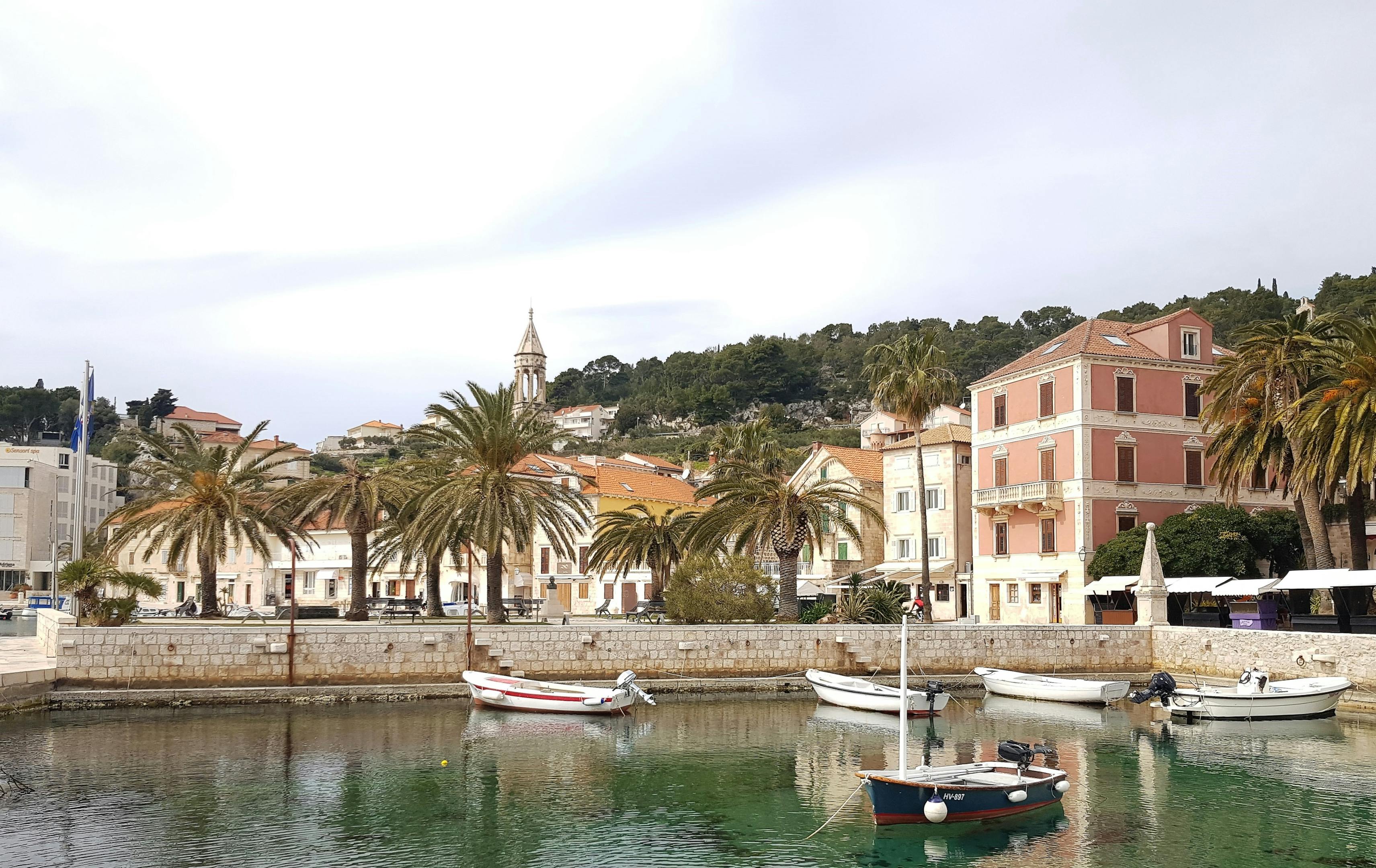 Beautiful harbor in Hvar with boats, historic buildings, and palm trees