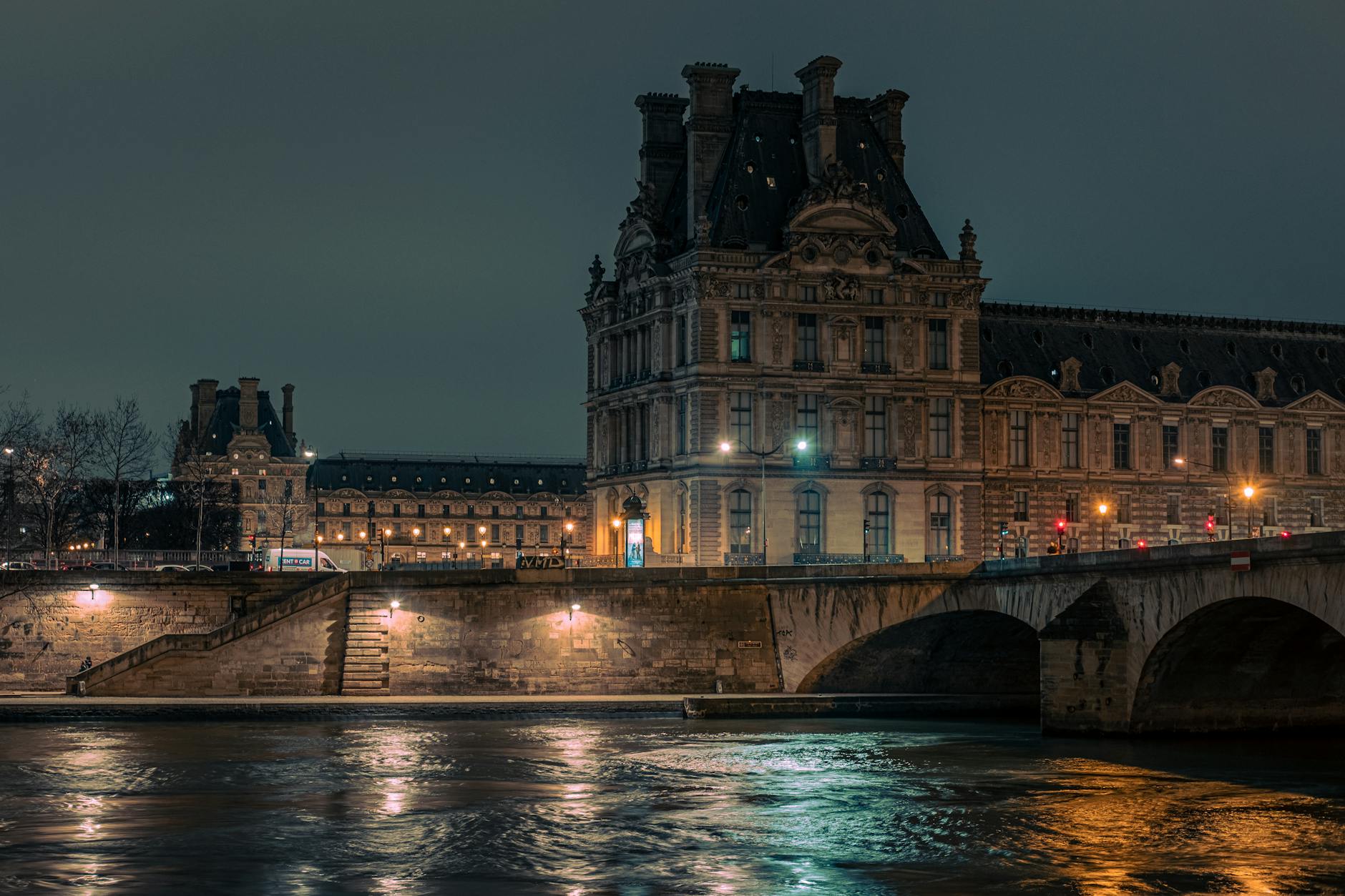 The illuminated Louvre Museum by the Seine river at night