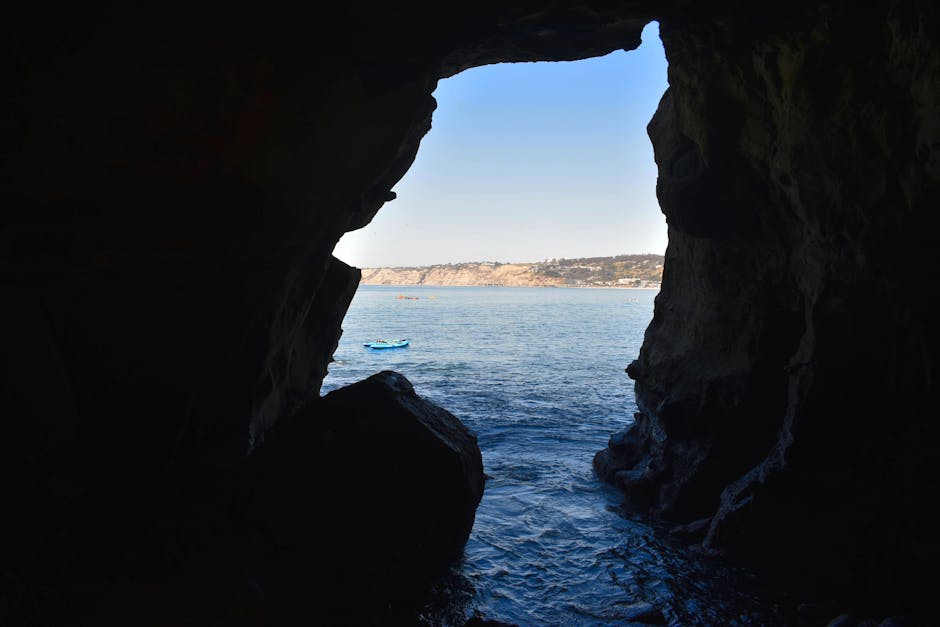 Kayakers paddling through a sea cave with light filtering through