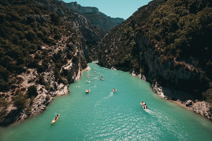 Kayakers paddling through turquoise water surrounded by steep canyon walls