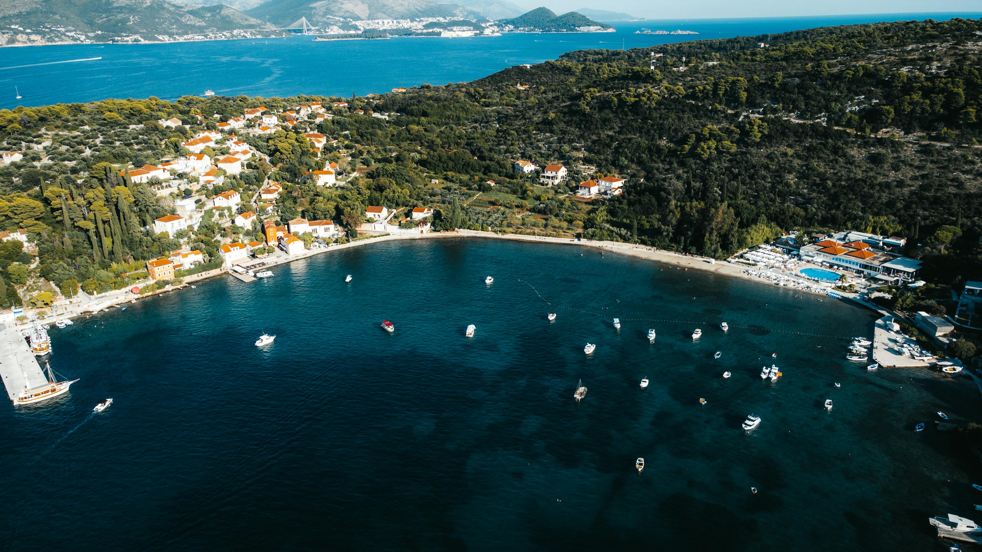 A breathtaking aerial view of Kolocep Island's coastline with boats and lush greenery in Croatia