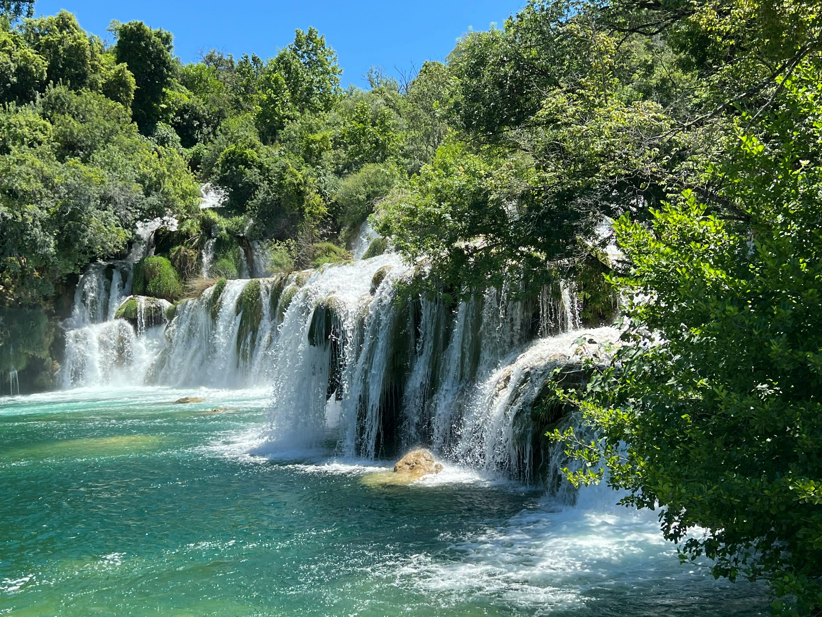Beautiful cascading waterfall surrounded by lush greenery under clear blue skies