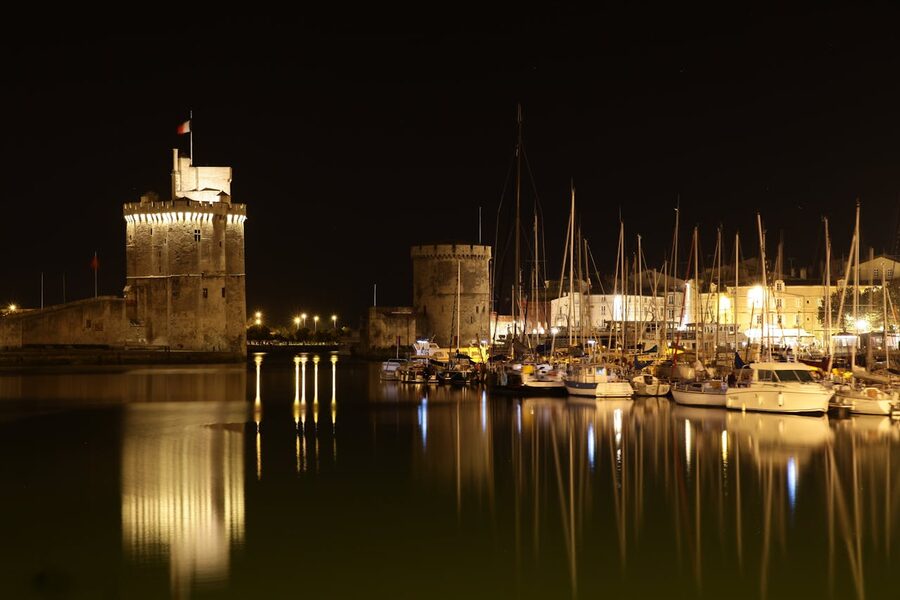 La Rochelle harbor at night with illuminated historic towers reflecting on water
