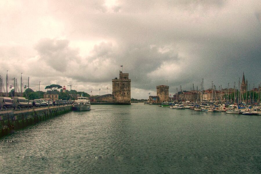 La Rochelle harbor with historic towers under a cloudy sky