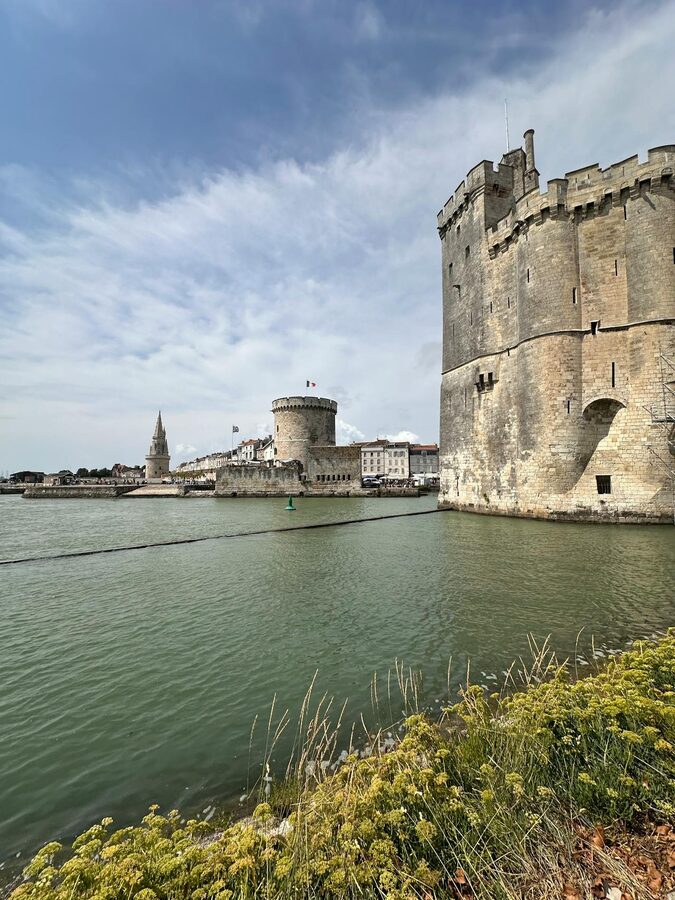 Dramatic view of La Rochelle harbor towers against a cloudy sky