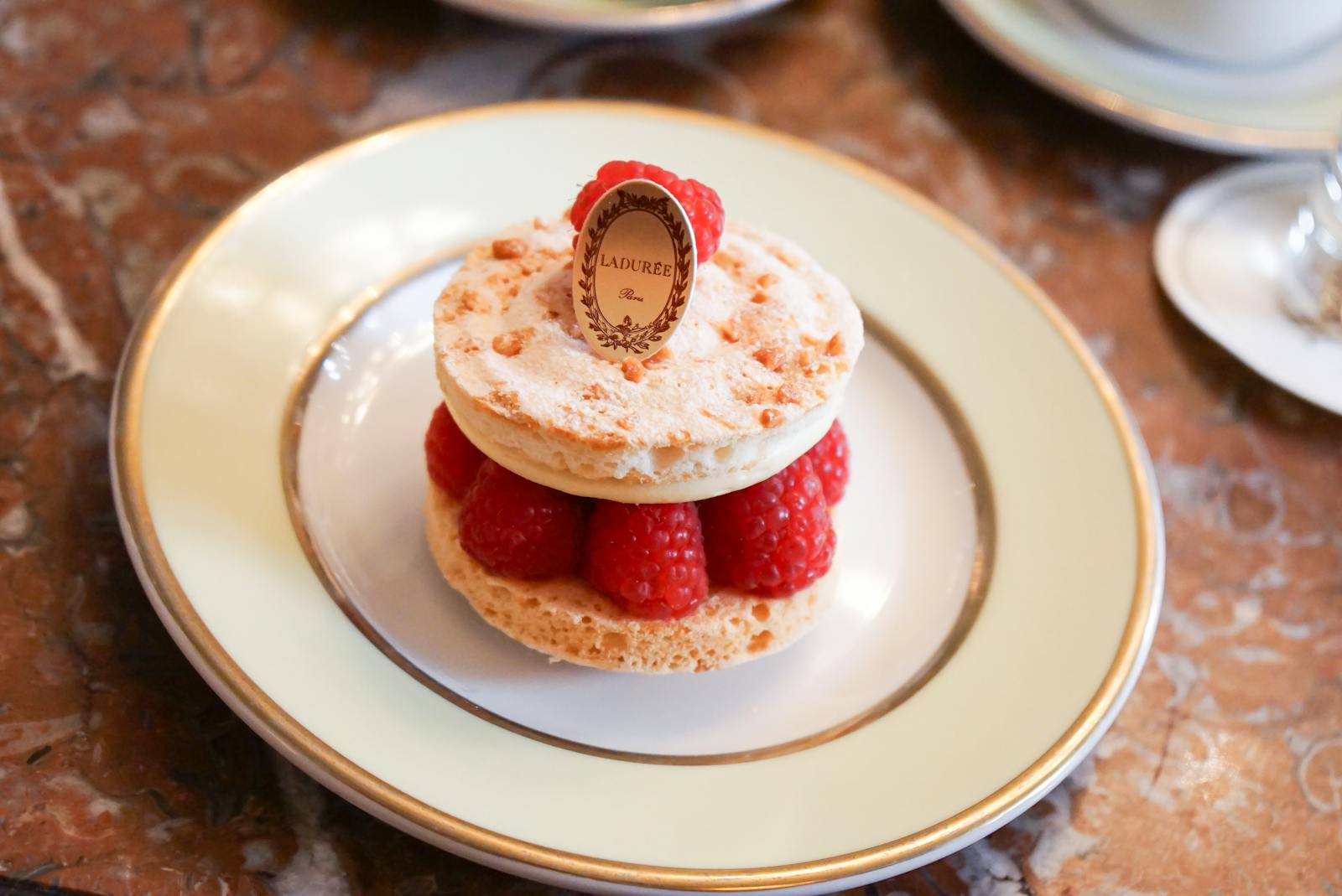 Ladurée raspberry macaron dessert elegantly plated at a Paris salon de thé