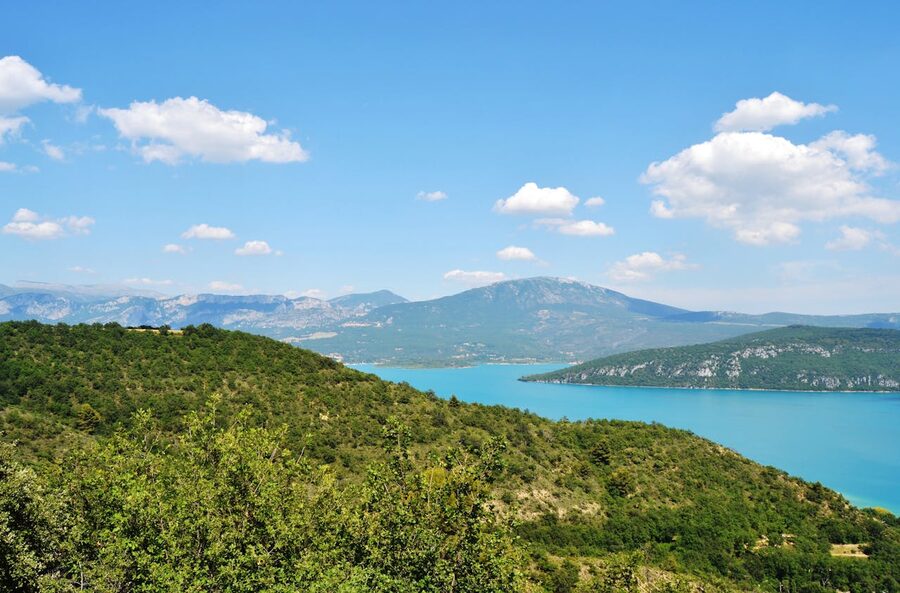 Lake Sainte-Croix surrounded by green hills and mountains under a blue sky