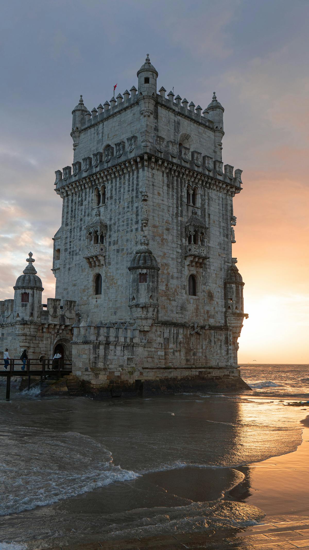 Belém Tower silhouetted against a vibrant sunset on the Lisbon coast