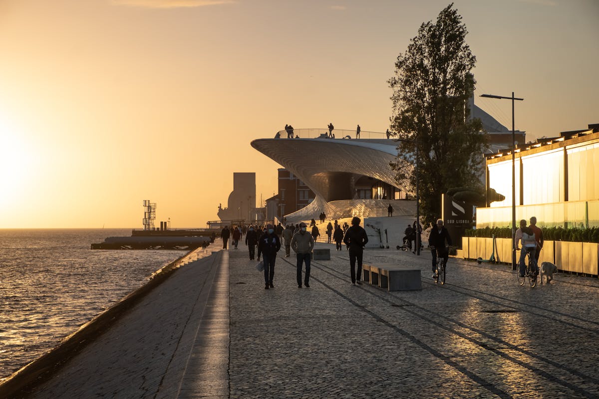 People walking by the MAAT Museum on Lisbon waterfront at golden hour