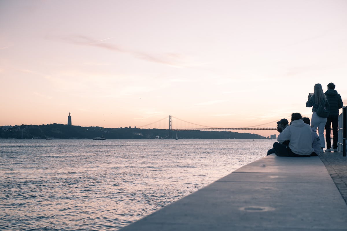 Sunset over Lisbon riverfront with 25 de Abril Bridge and Cristo Rei statue