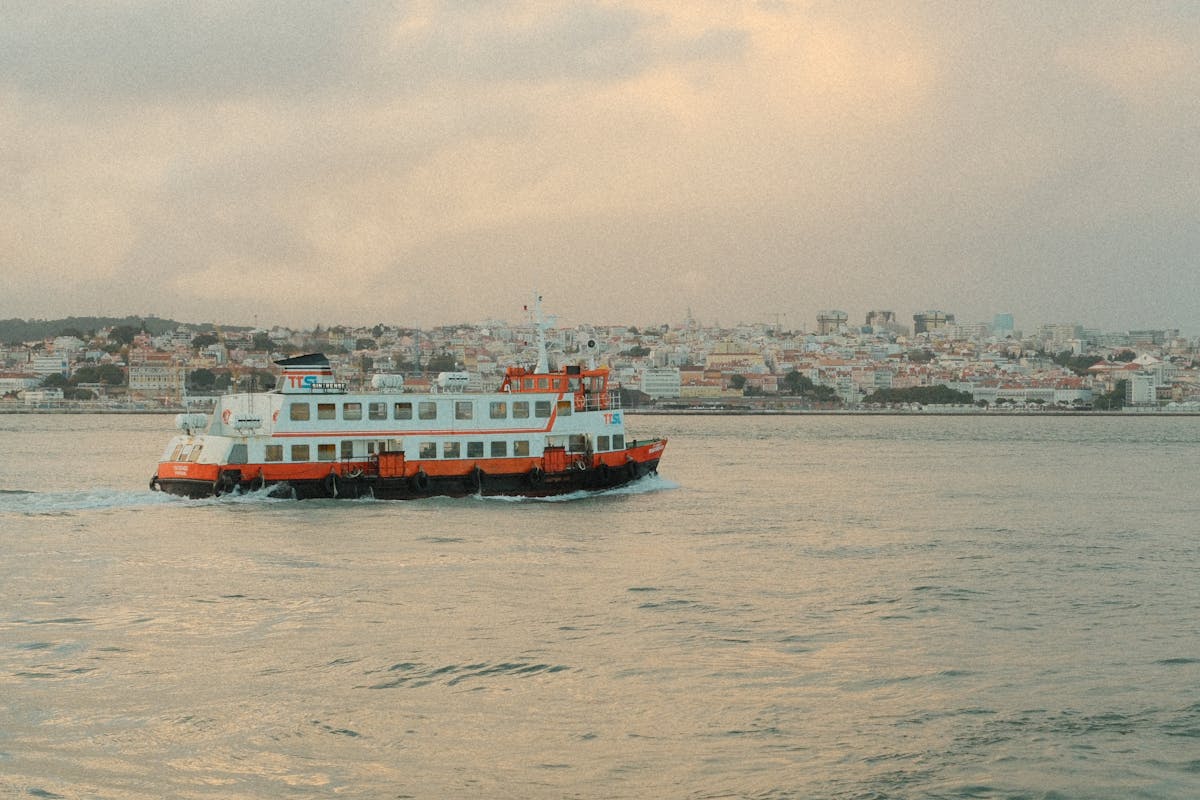 Traditional boat cruising the Tagus River in Lisbon at dusk