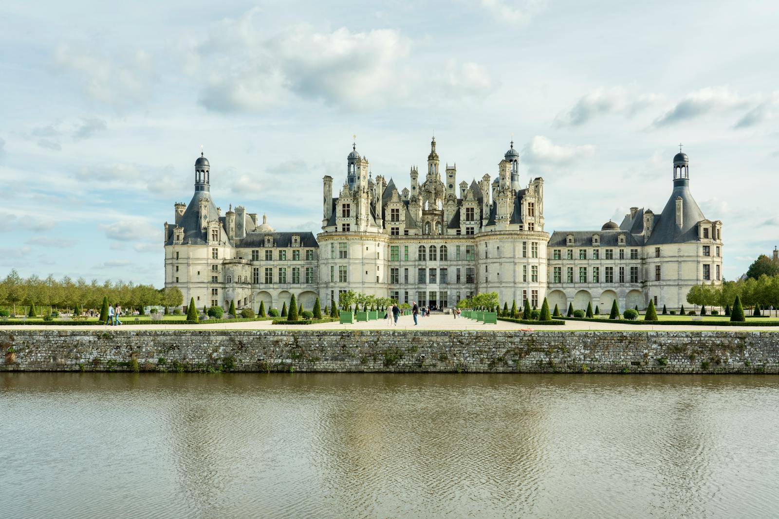 Chateau de Chambord reflecting in the water under a bright sky in France