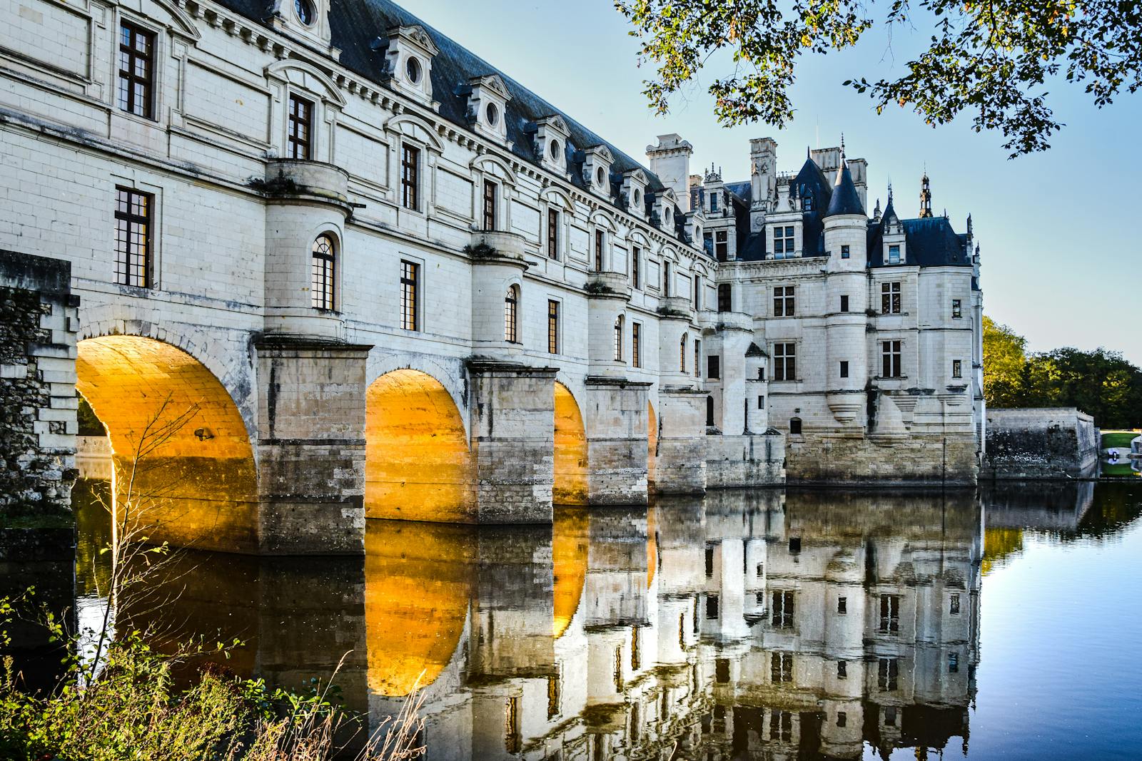 Chateau de Chenonceau illuminated arches glowing at dusk above the Cher River