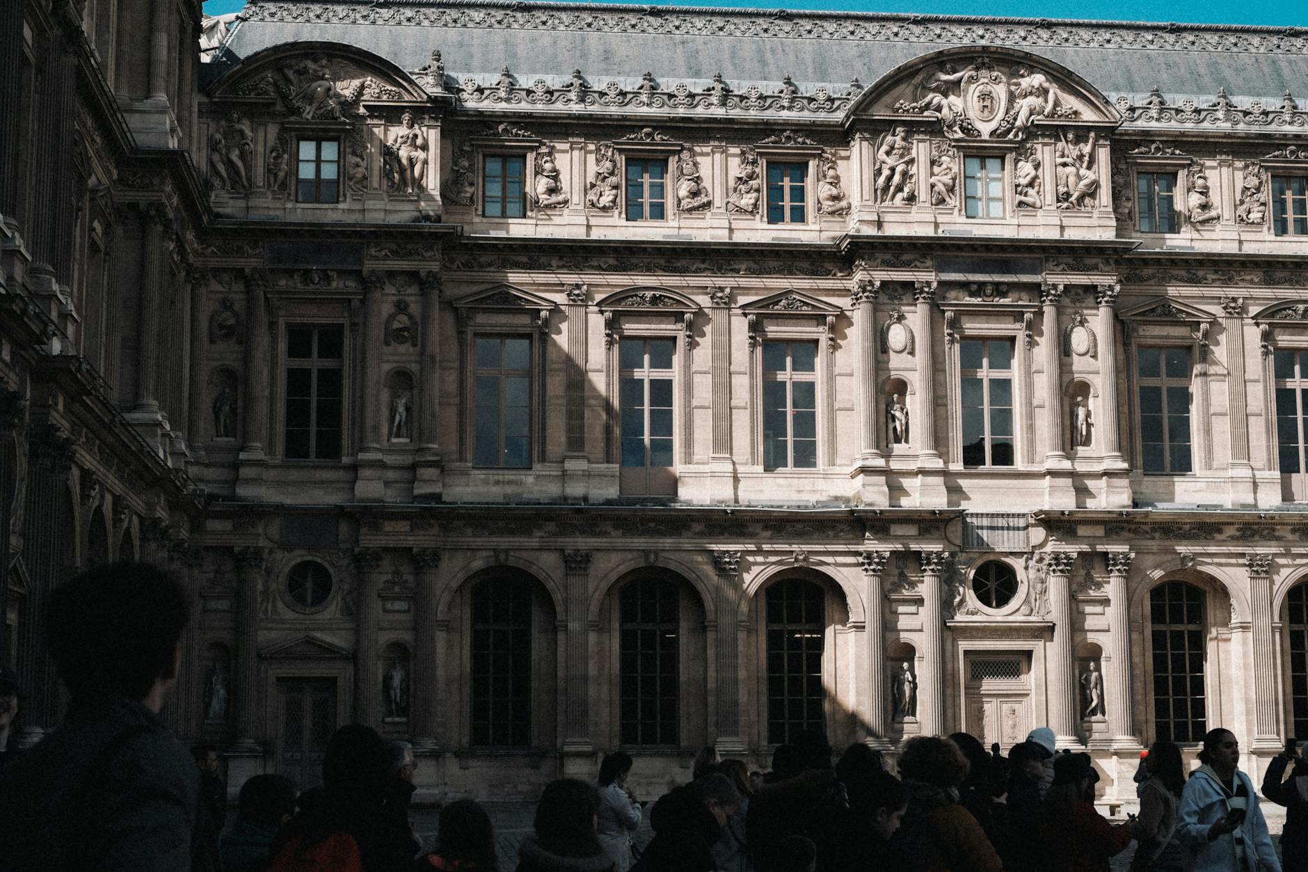 The Baroque facade of the Louvre Museum with a crowd