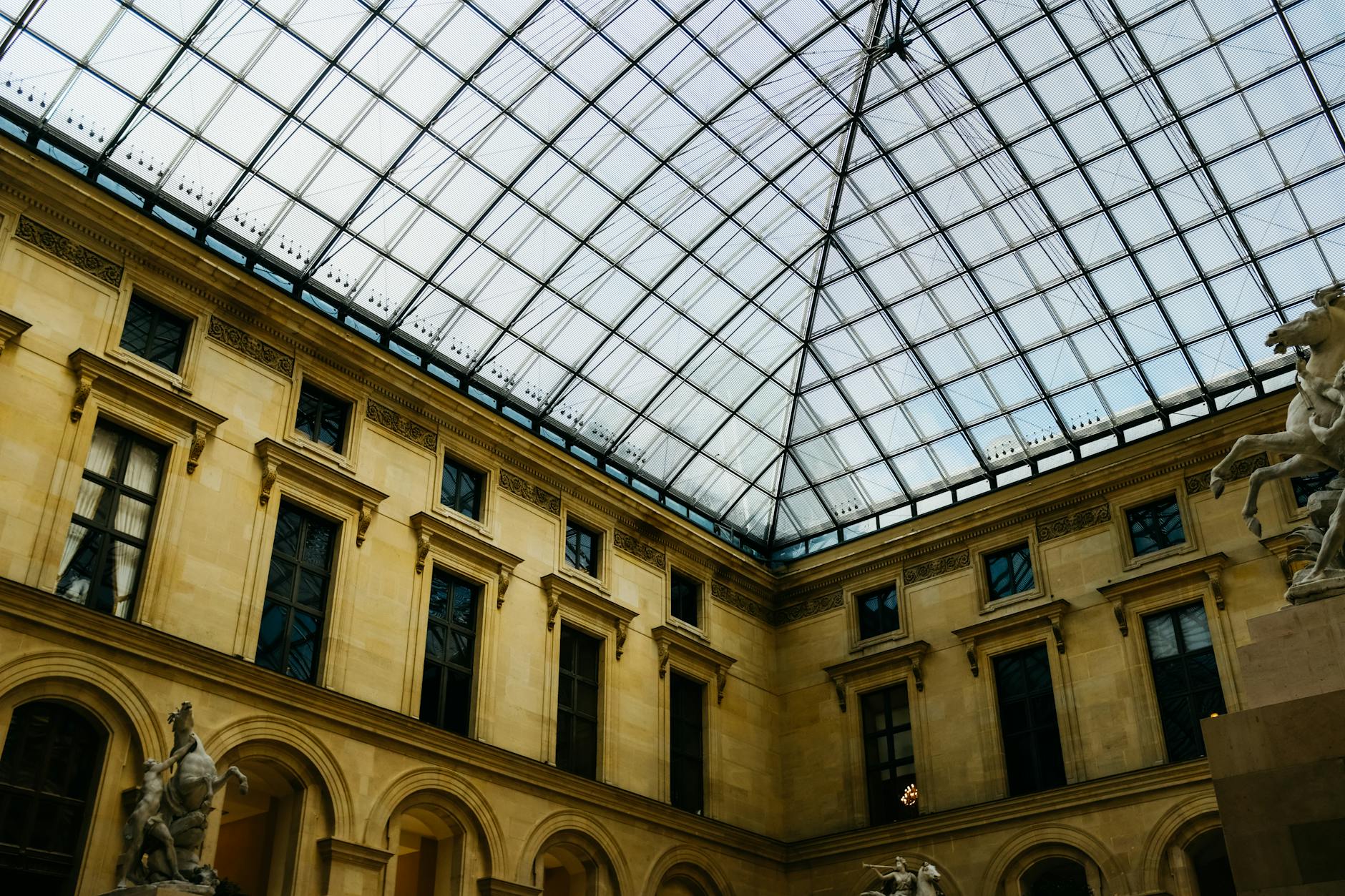 The interior of the Louvre with a glass ceiling and classical sculptures