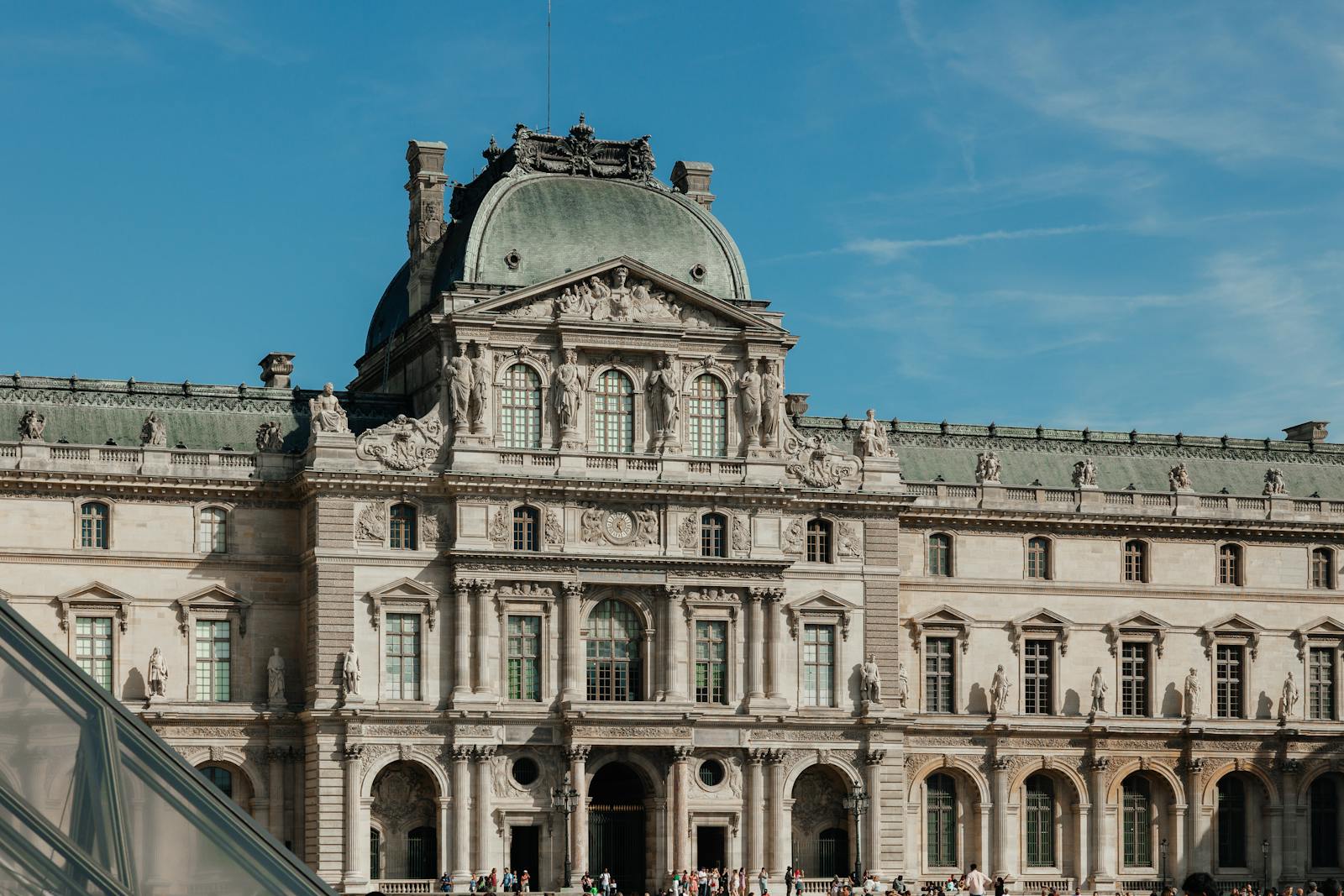 Exterior view of the historic Louvre Museum under a clear blue sky