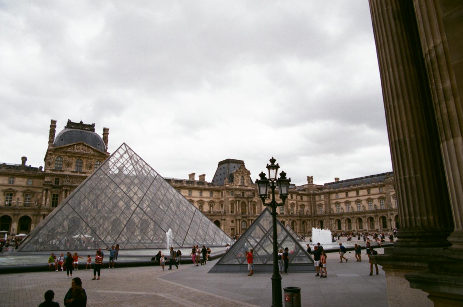 View of the Louvre Pyramid and Napoleon Courtyard with travelers in Paris