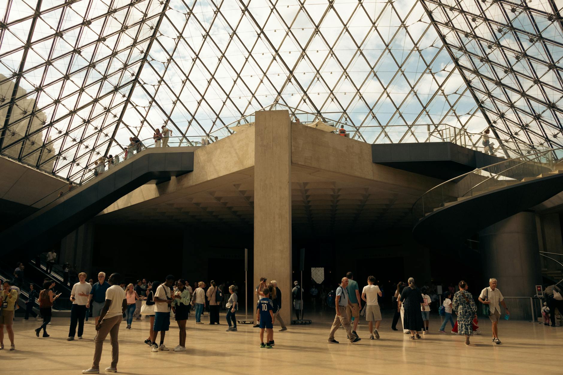 The busy pyramid entrance to the Louvre Museum with visitors