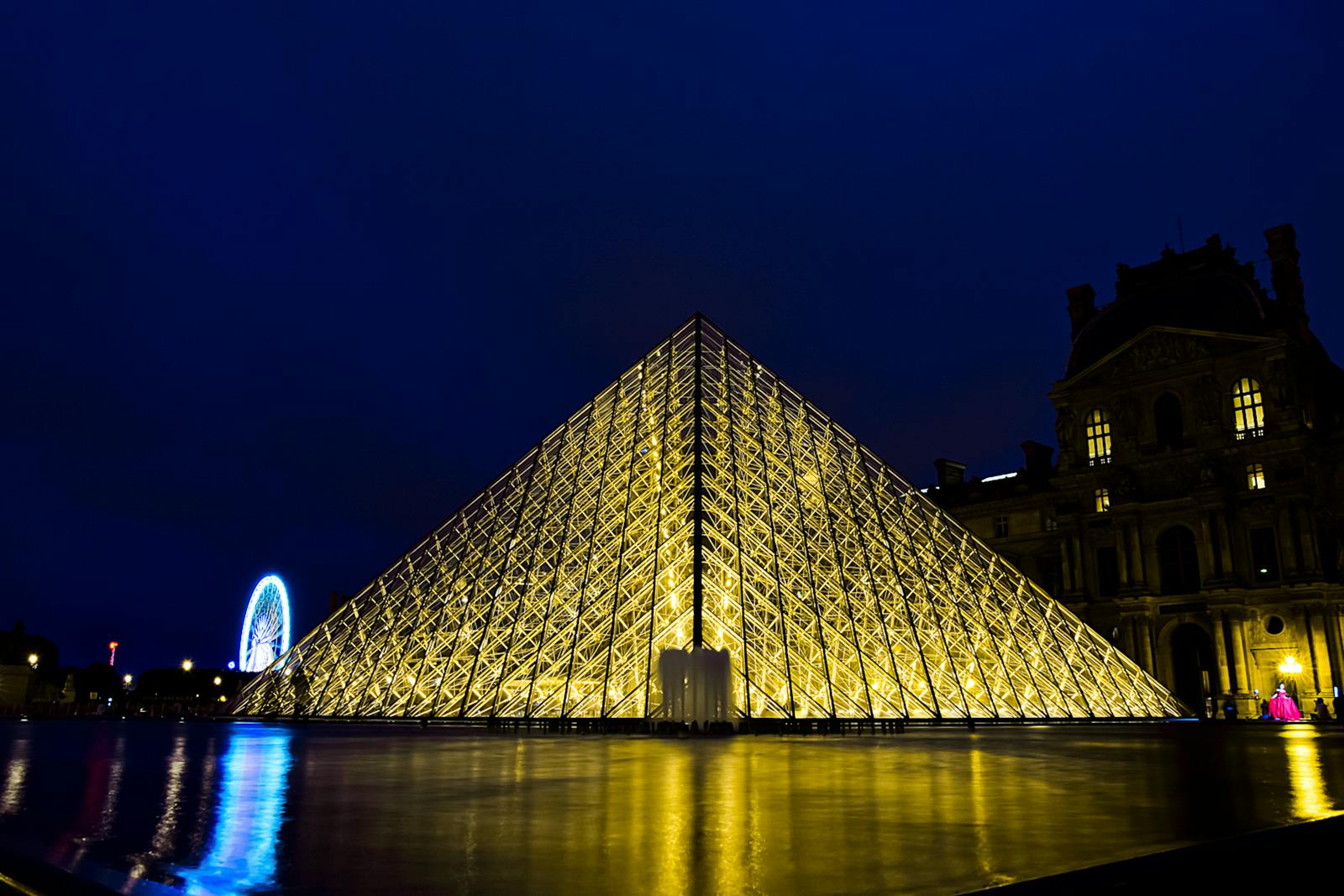 Louvre Pyramid illuminated at night with golden lights in Paris