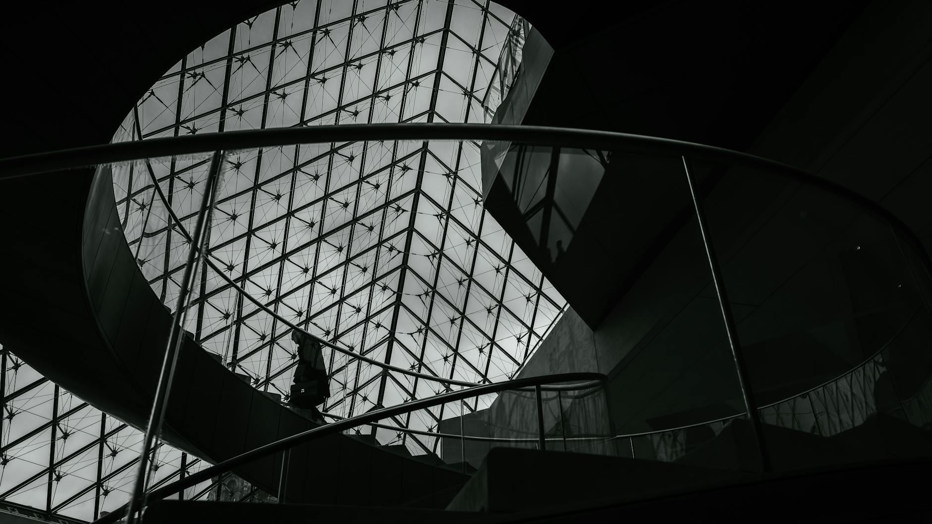 A silhouette of a person on the spiral staircase inside the Louvre Pyramid