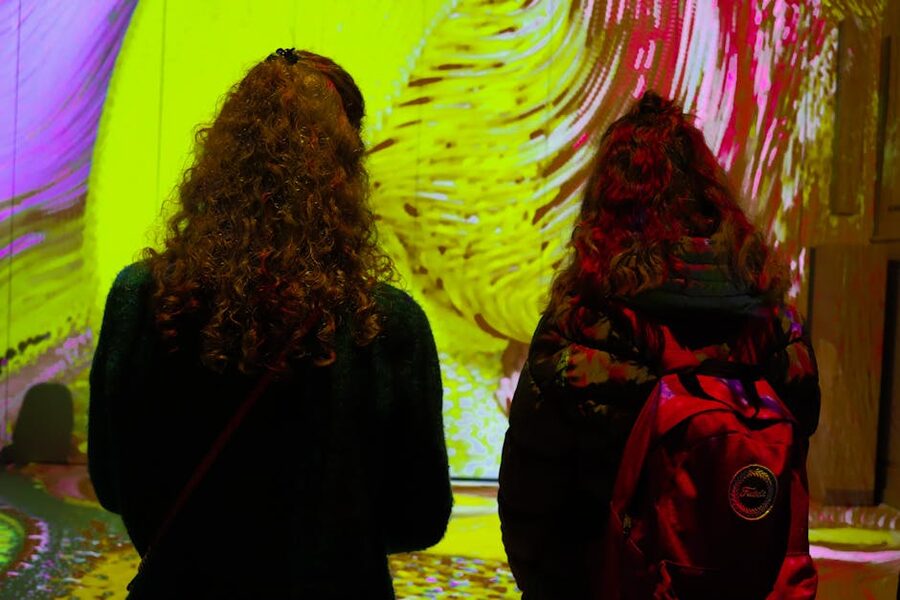Two women with curly hair observe colorful projections
