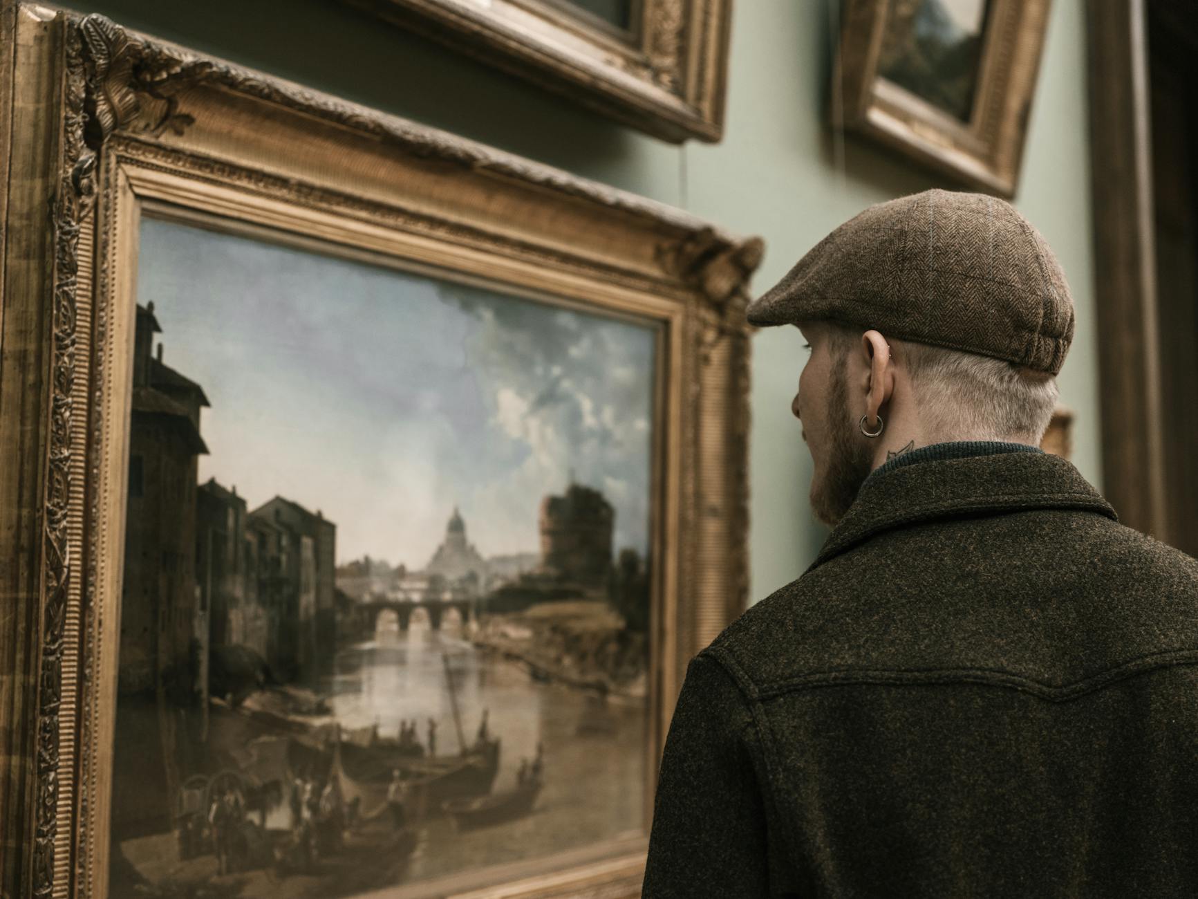 A man observing a classic landscape painting in a museum setting