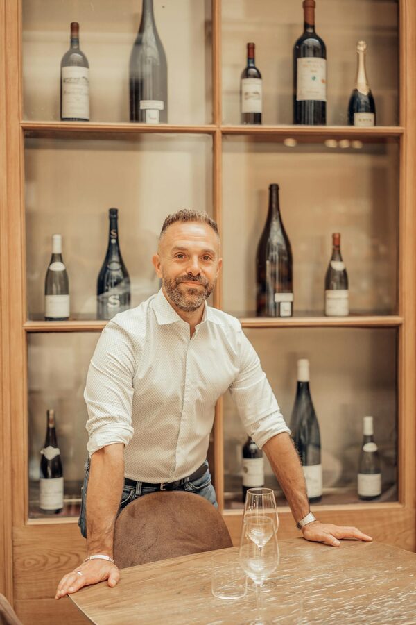 Man standing by wooden racks with wine bottles in Paris