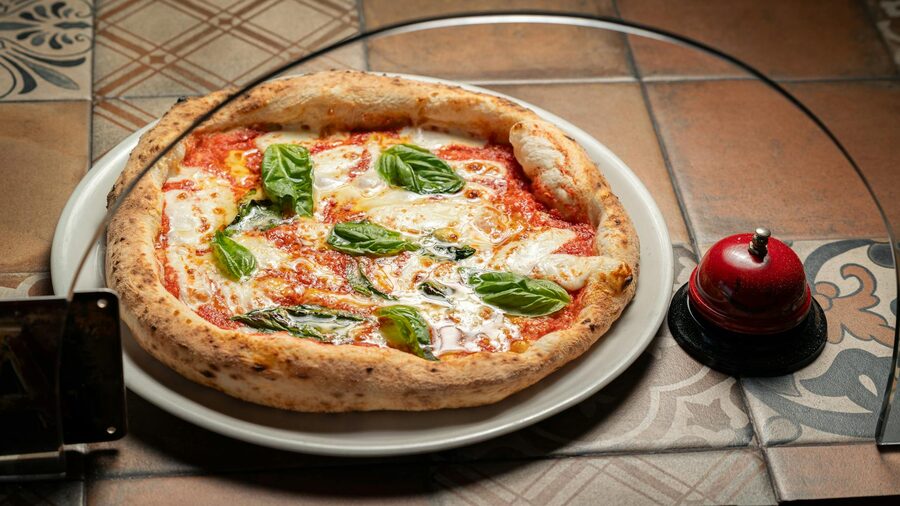 Margherita pizza with fresh basil on a rustic tiled table