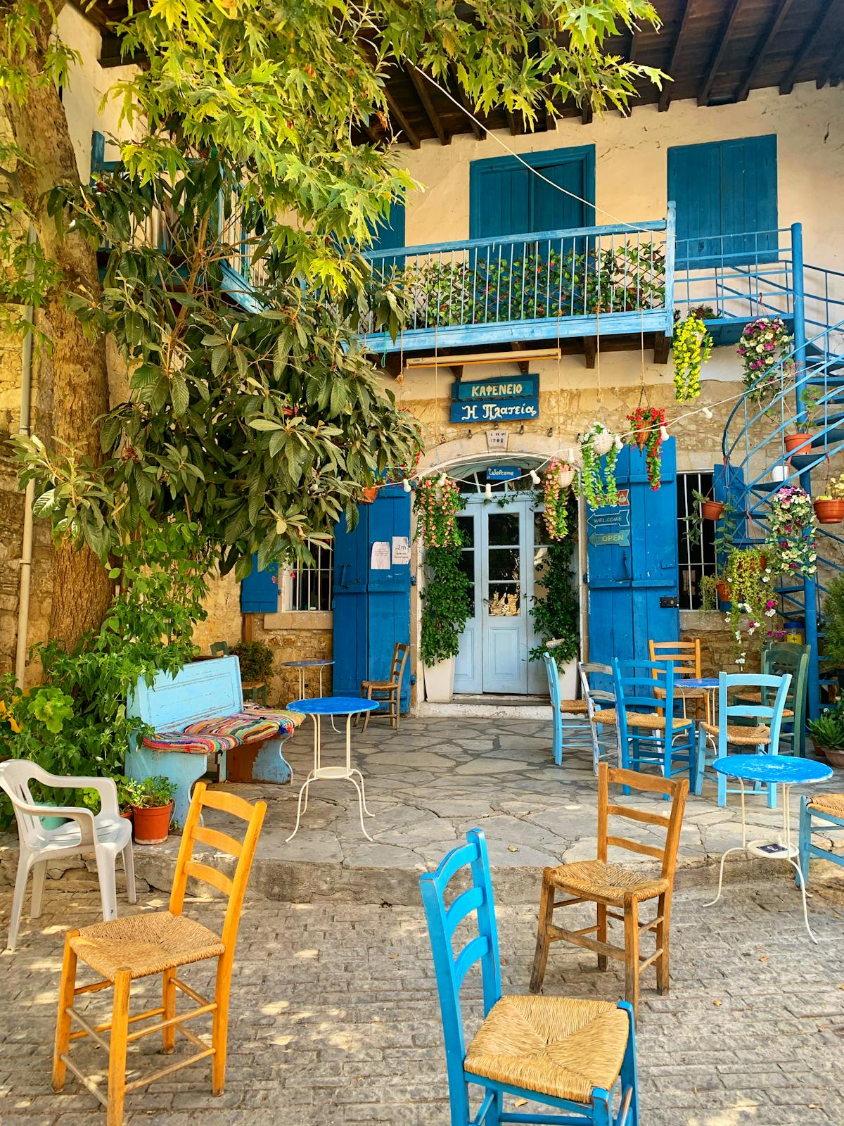 Colourful outdoor café chairs and tables in a Mediterranean setting with greenery