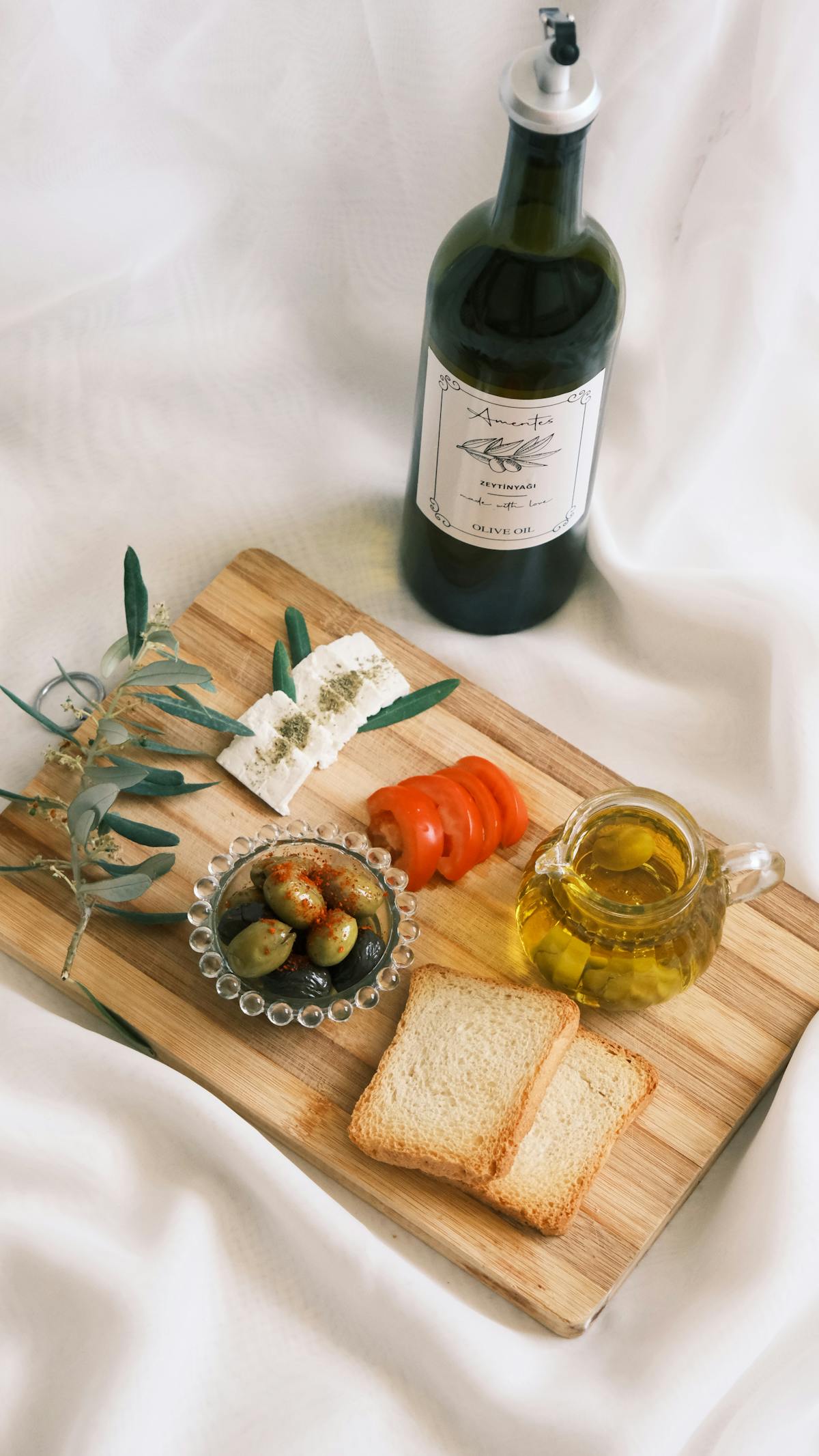 Mediterranean snack board with olive oil, cheese, olives, and tomatoes