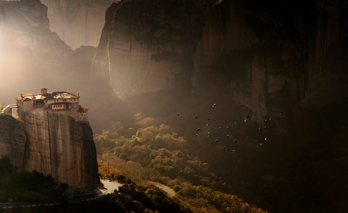 Meteora monastery on a cliff at sunset with stunning landscape