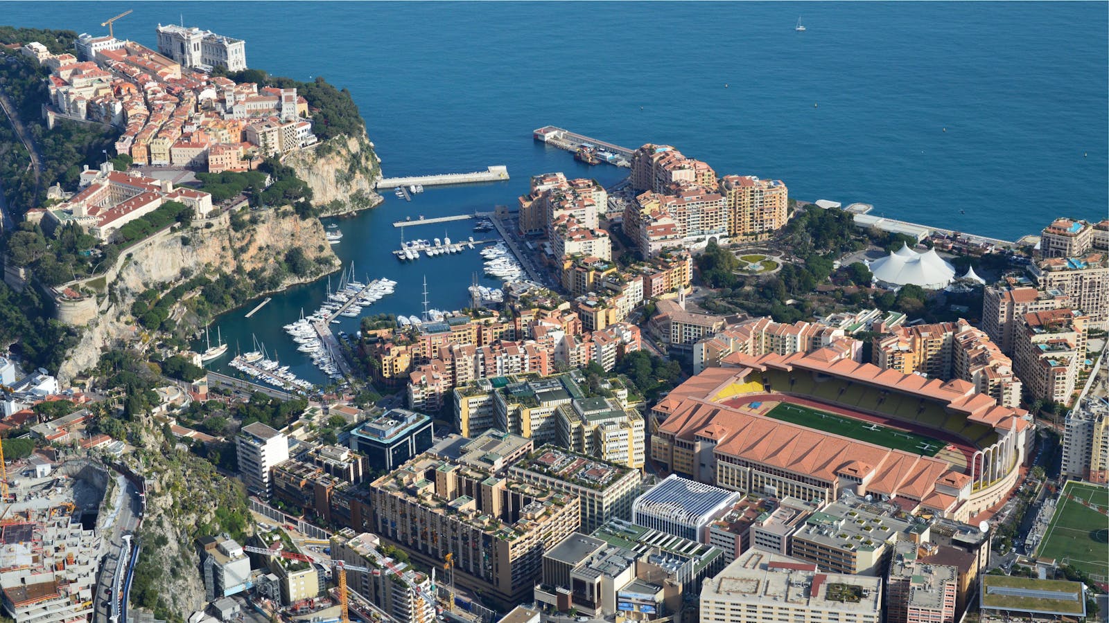 Aerial view of Monaco's coastal cityscape with harbors and the Mediterranean Sea