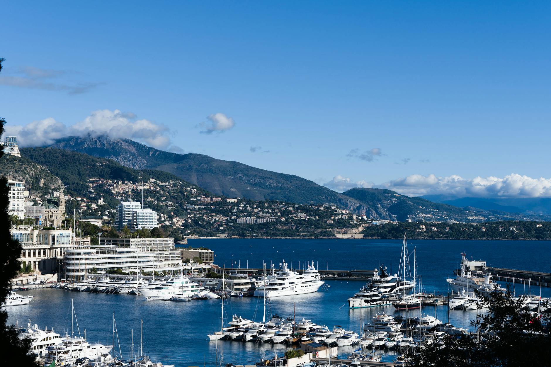 Monaco harbor with luxury yachts and mountains on a clear day