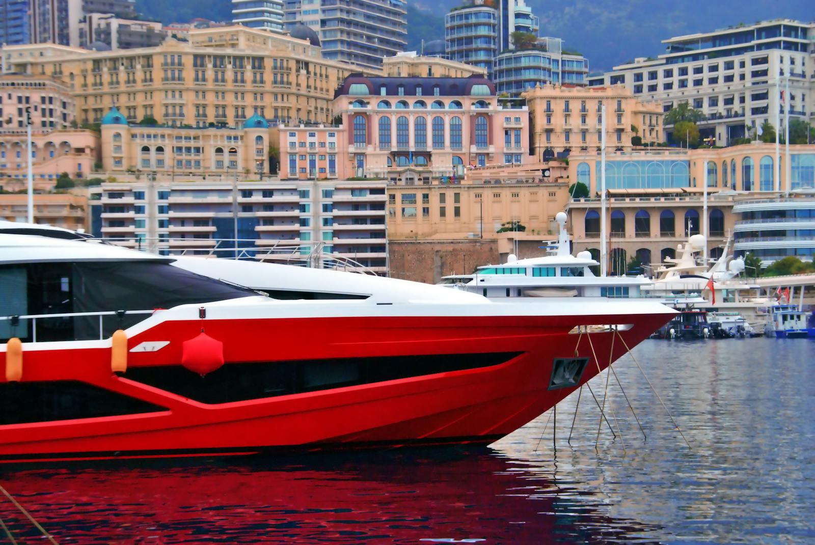 A red yacht moored at the scenic harbor of Monaco surrounded by elegant architecture