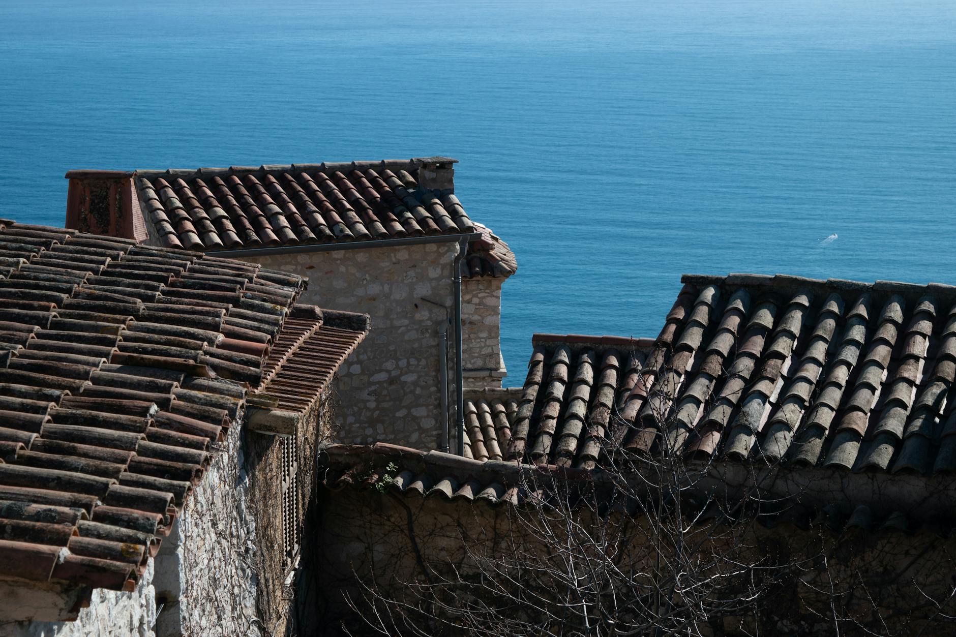 Terracotta rooftops with views of the Monaco coastline under bright daylight
