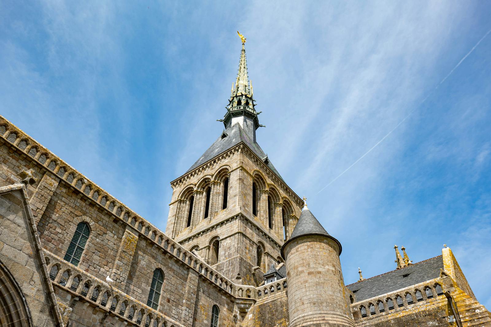 Mont Saint-Michel Abbey spire reaching into a clear blue sky