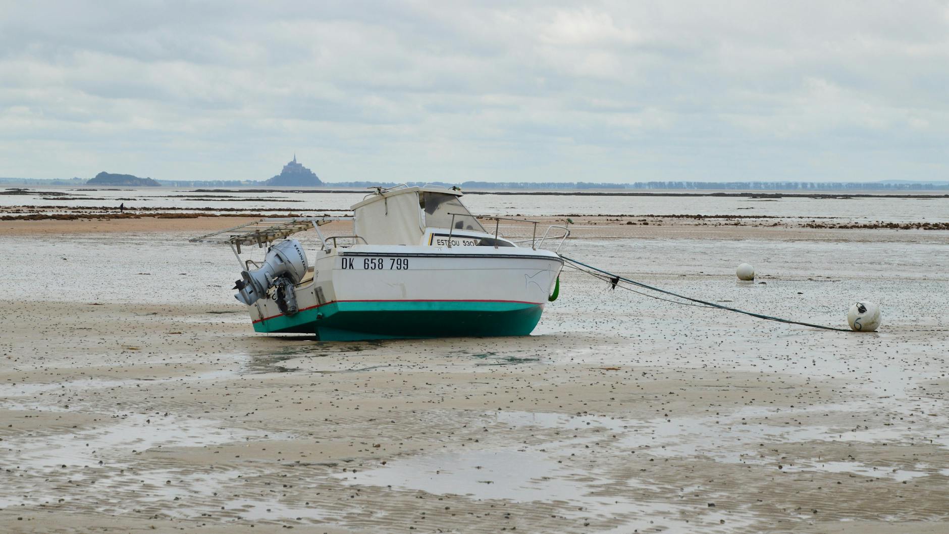 Beached boat at low tide with Mont Saint-Michel in the distance