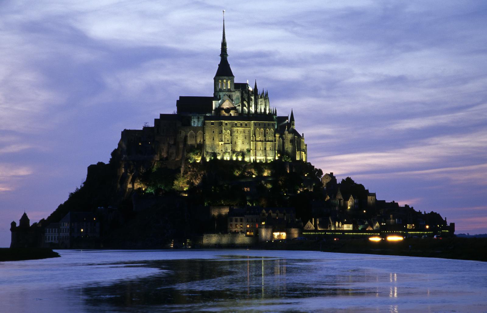 Mont Saint-Michel illuminated at sunset glowing against the evening sky