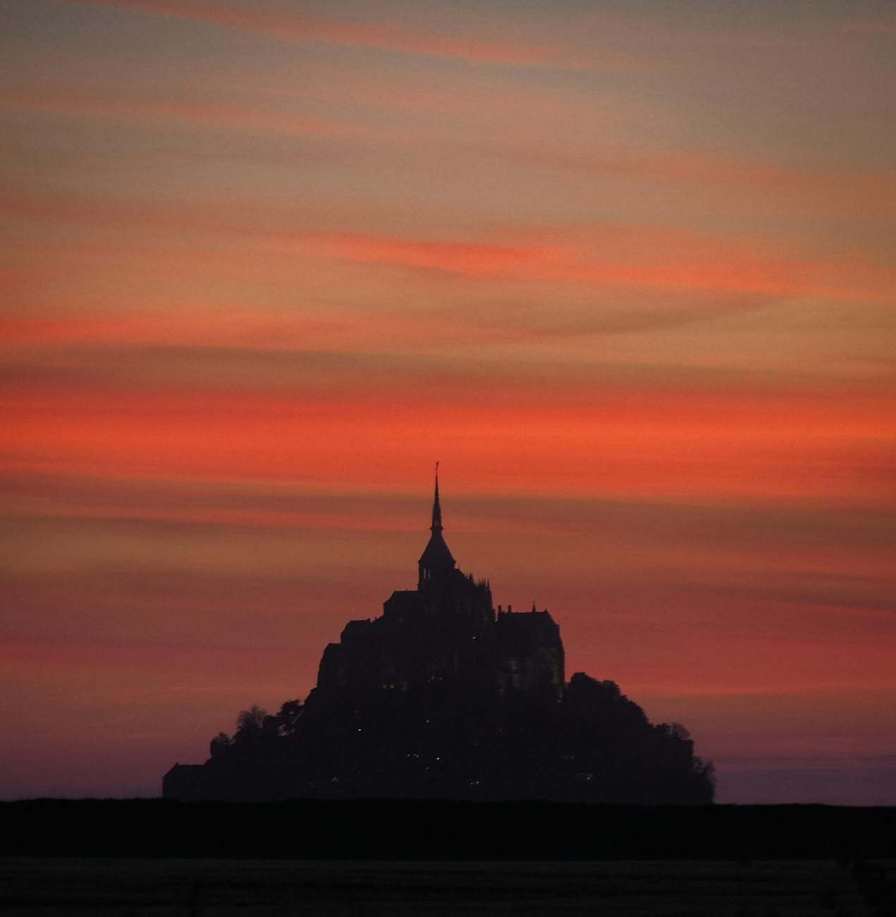 Dramatic silhouette of Mont Saint-Michel at sunset in Normandy