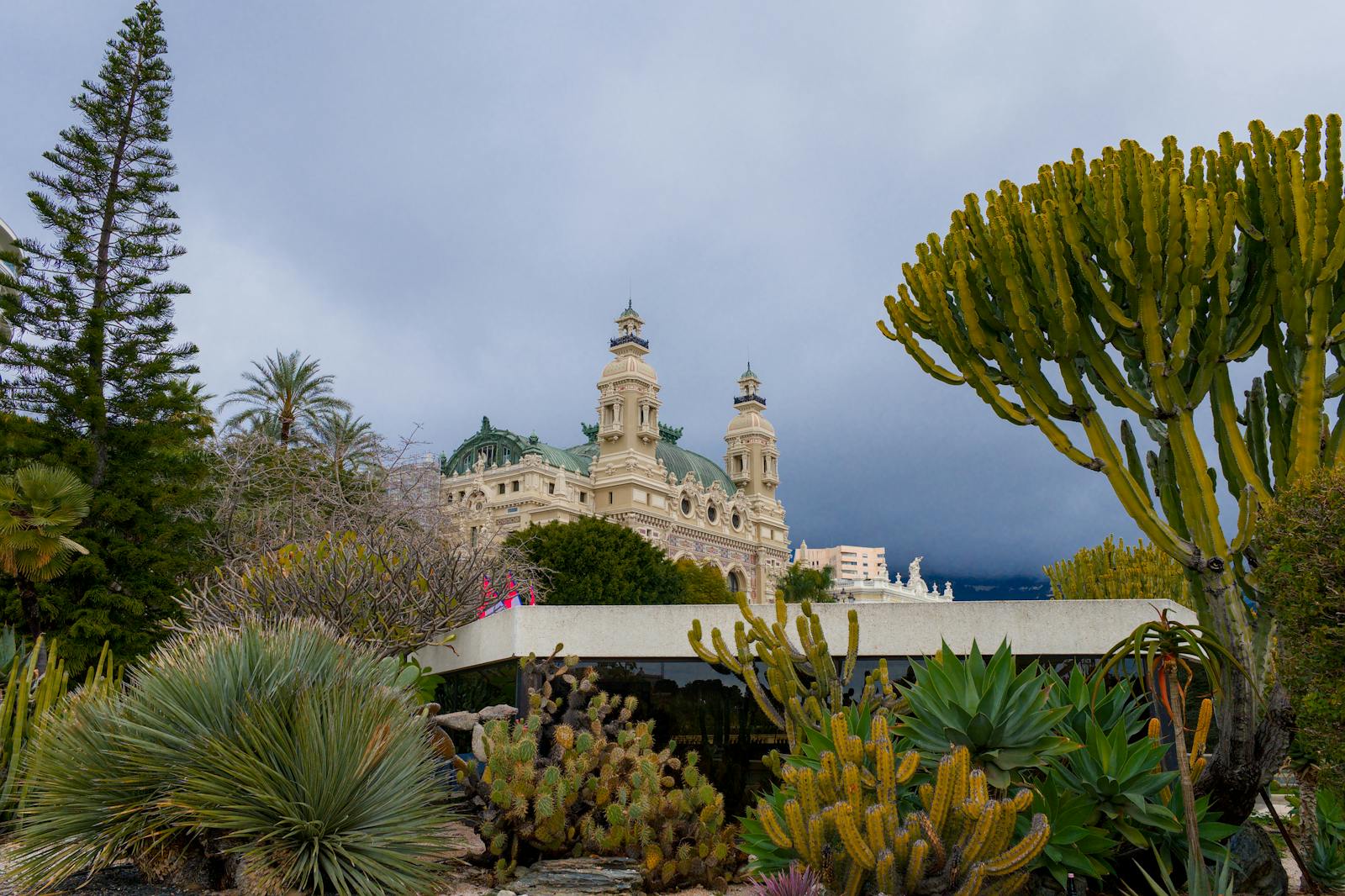 Monte Carlo Casino surrounded by diverse cacti and foliage under a cloudy sky