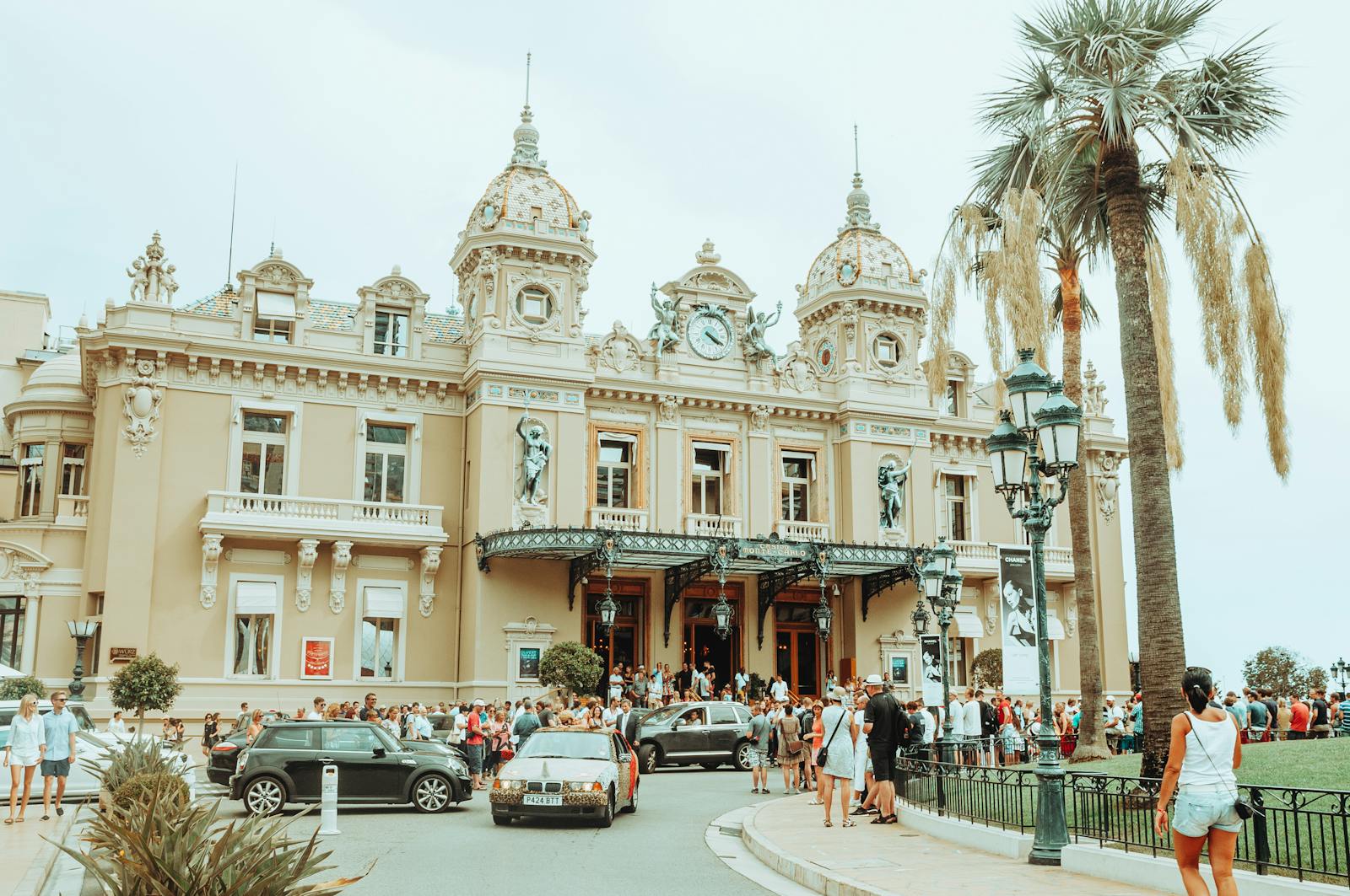 The iconic Monte Carlo Casino exterior with palm trees and luxury cars on a sunny day