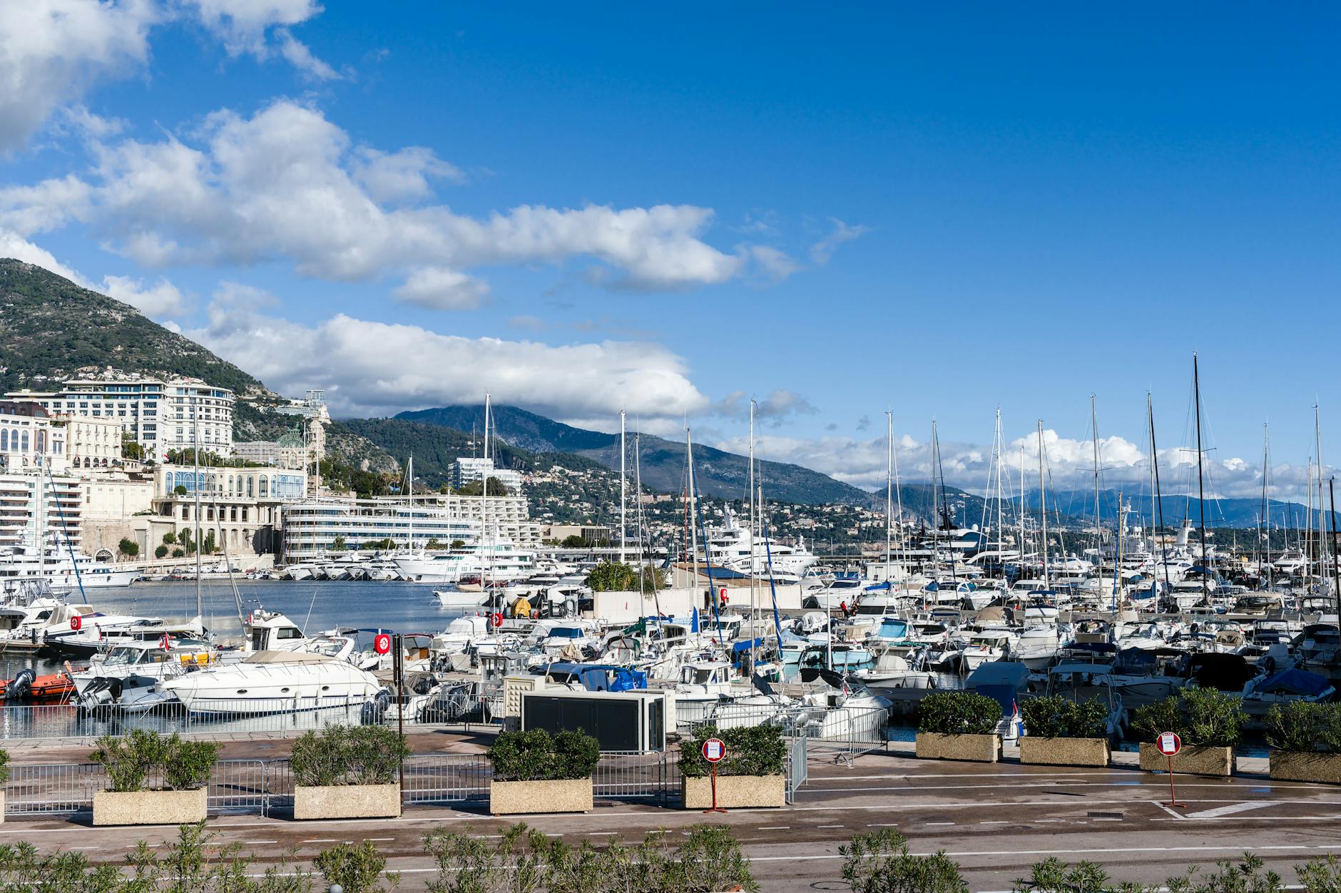 Monte Carlo harbor with yachts and mountains in the background on a clear day