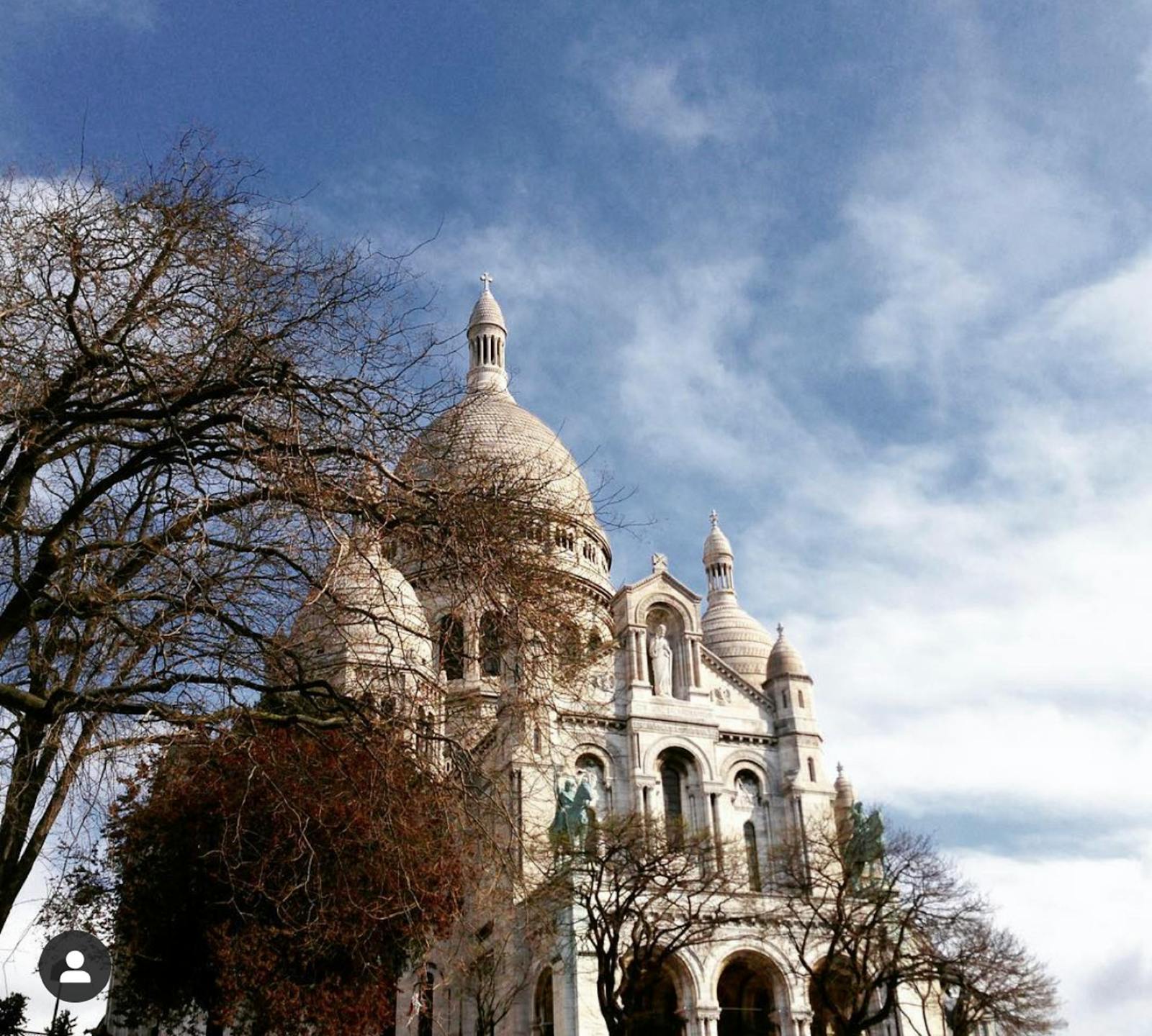 Sacre-Coeur Basilica in Paris framed by trees under a clear blue sky