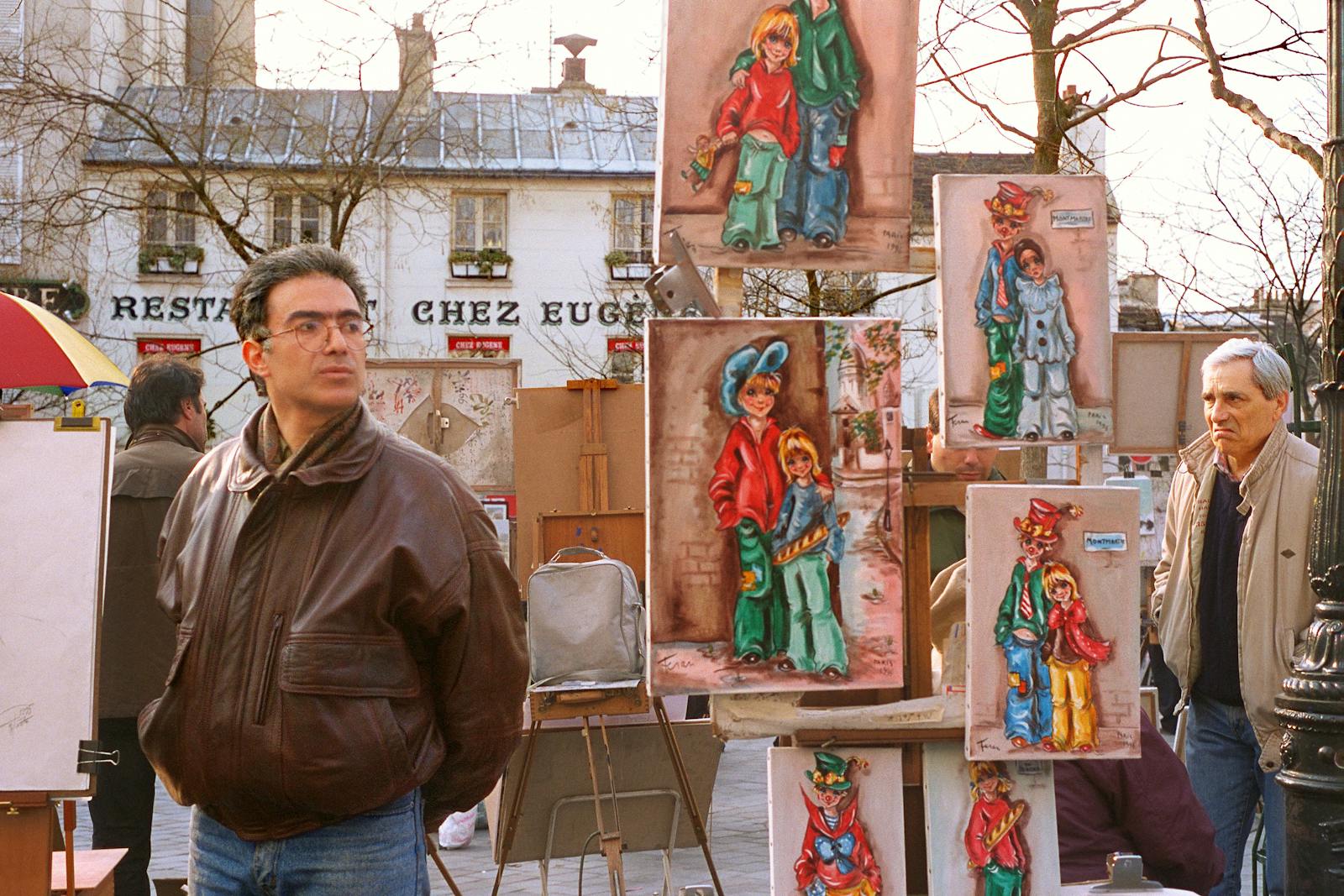 People observing colorful street art displays in Montmartre Paris