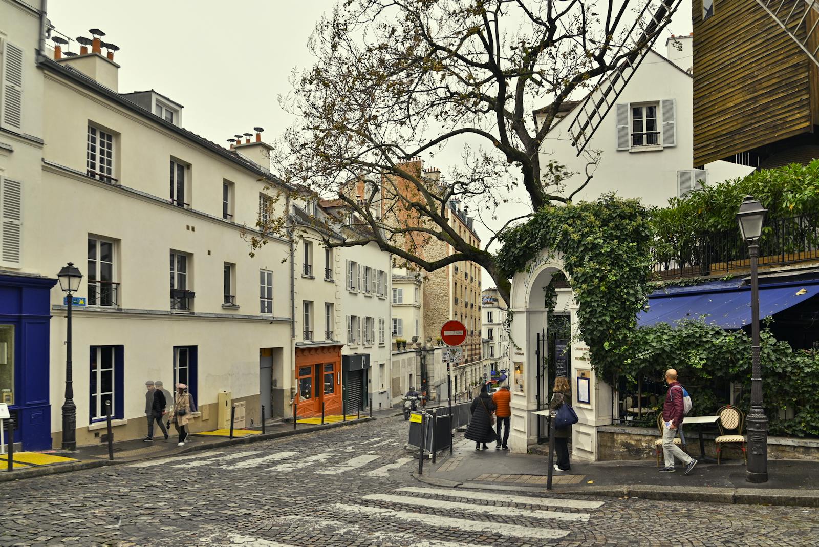 Historic Montmartre street with a surviving windmill framed by autumn leaves in Paris