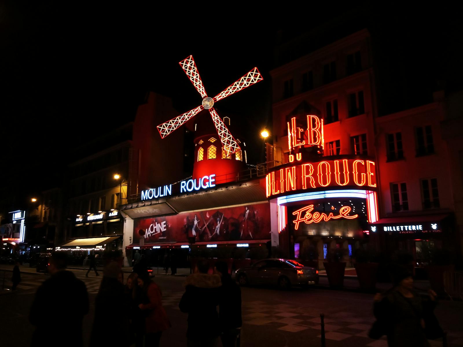 Moulin Rouge cabaret exterior with glowing neon lights in Paris at night