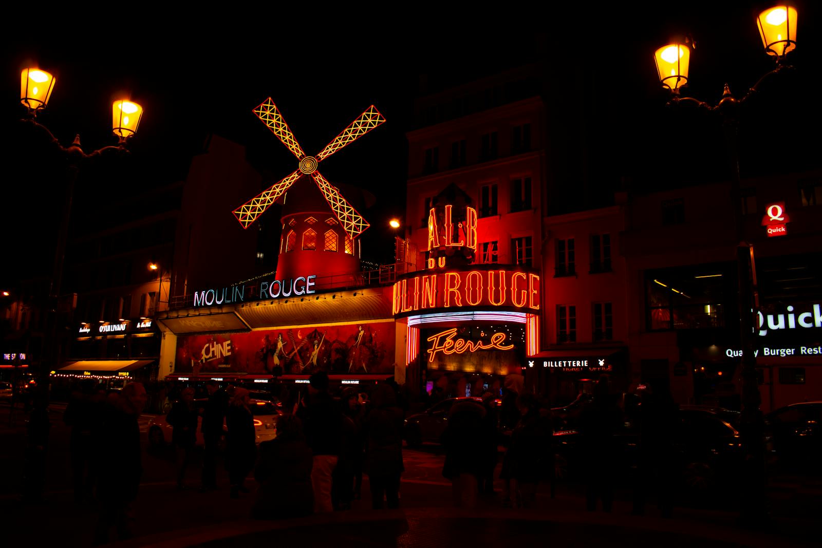 Illuminated night scene of the Moulin Rouge in Paris with the famous red windmill glowing