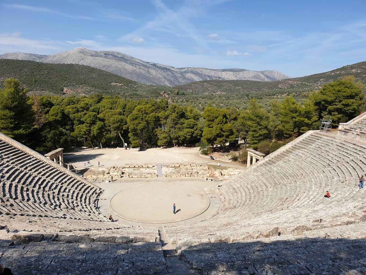 The ancient theater of Epidaurus surrounded by lush green trees and Mediterranean vegetation