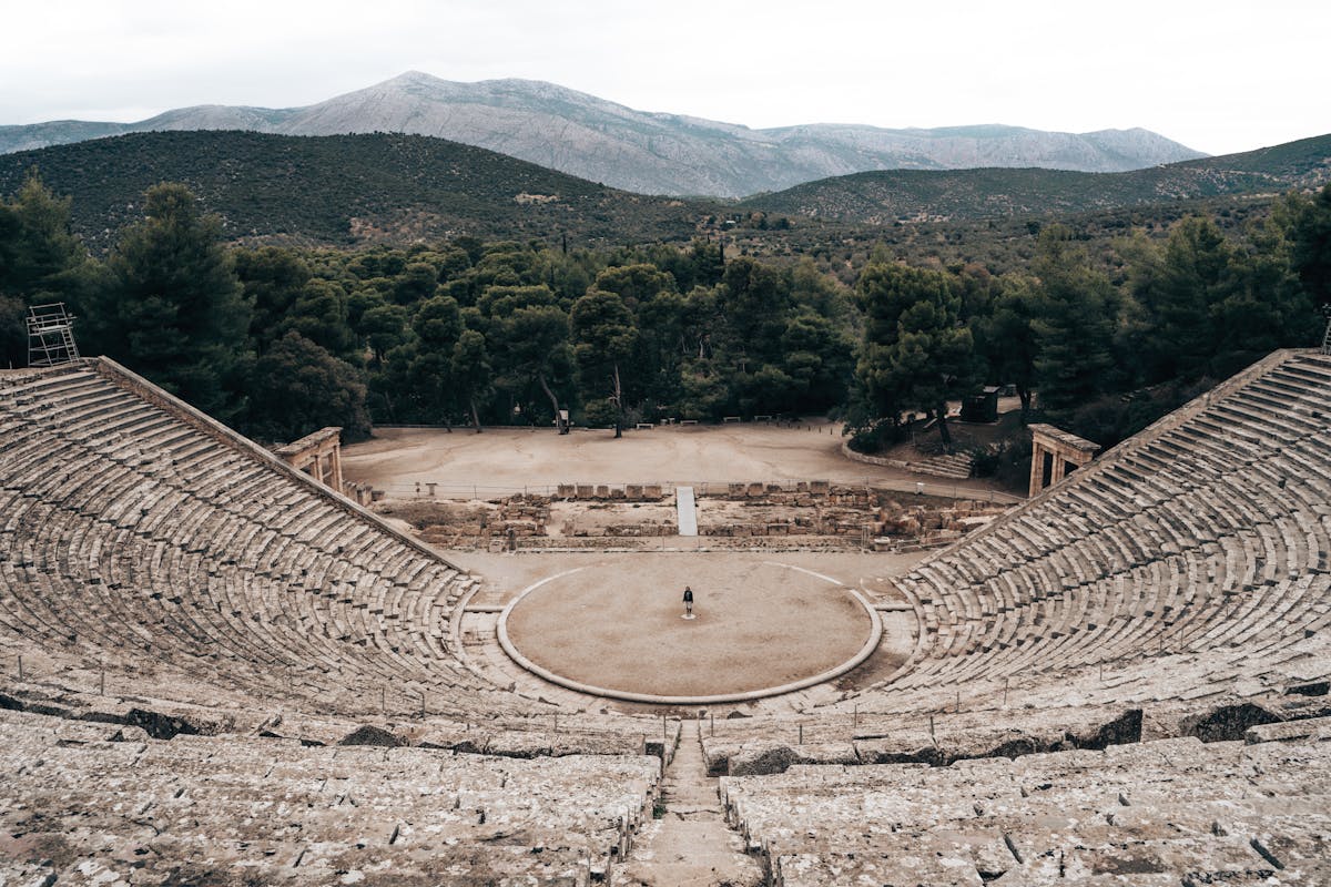 Ancient Greek theater surrounded by Mediterranean greenery with rows of stone seating